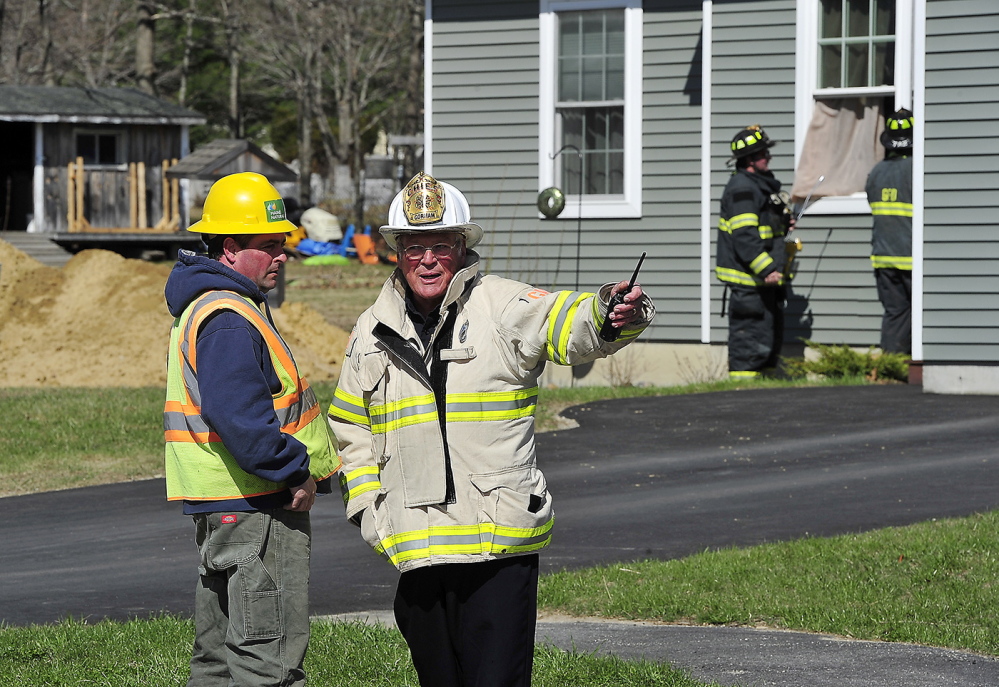 Gorham firefighters open the windows to this unoccupied home as Gorham Fire Chief Robert Lefevre talks with a Maine Natural Gas representative after an excavator being used to build new housing foundations ruptured a gas line main at Hawkes Farm development in Gorham.
