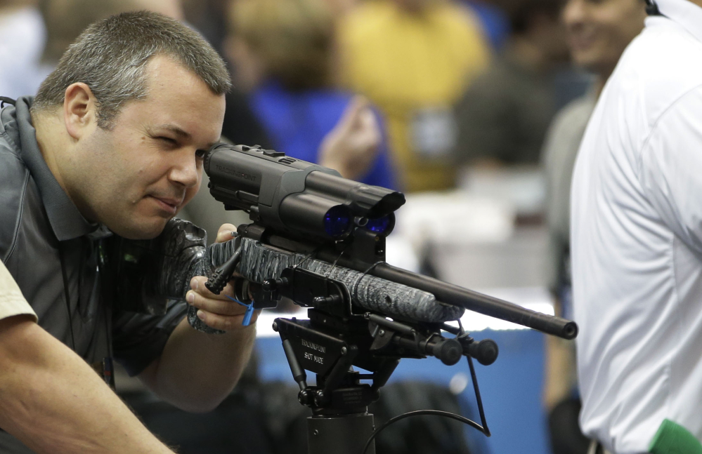 Mike Cisewski of Maple Plain, Minn., looks through a scope at the National Rifle Association’s annual convention Friday at Lucas Oil Stadium in Indianapolis.
