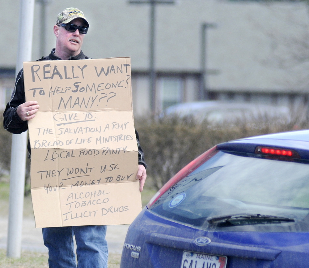 Augusta Police Chief Robert Gregoire speaks with a driver Friday while carrying a sign that discourages motorists from giving money to panhandlers at Memorial Circle.