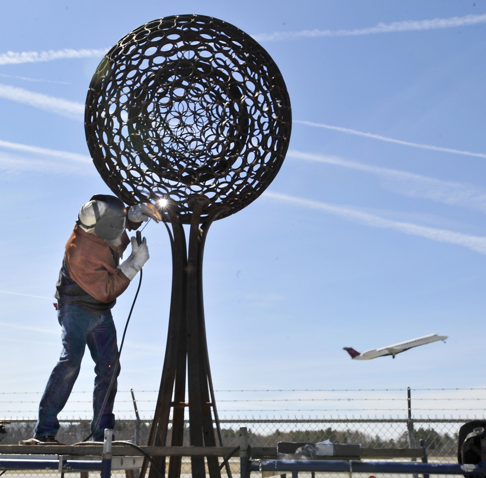 Sculptor Jay Sawyer of Warren installs “A Spirit of Its Own” on the Jetport Access Road on Friday.