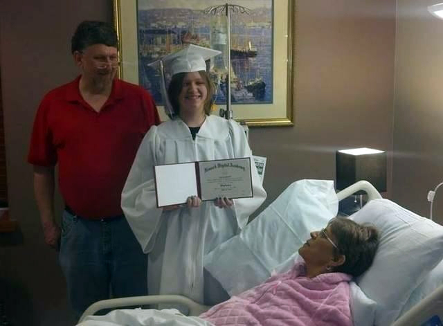 Melissa Shumaker, right, looks on as her 17-year-old daughter Evie Shumaker of Newport, Ohio, displays her diploma after a special high school graduation ceremony in the hospice at Licking Memorial Hospital in Newark, Ohio.