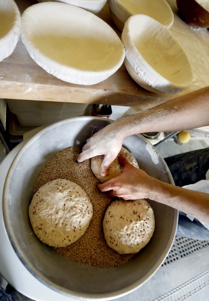 Olins coats dough rounds with seeds. He usually shows up for a Saturday morning market with a half-dozen varieties of breads, classic biscotti and pastries made from croissant dough.