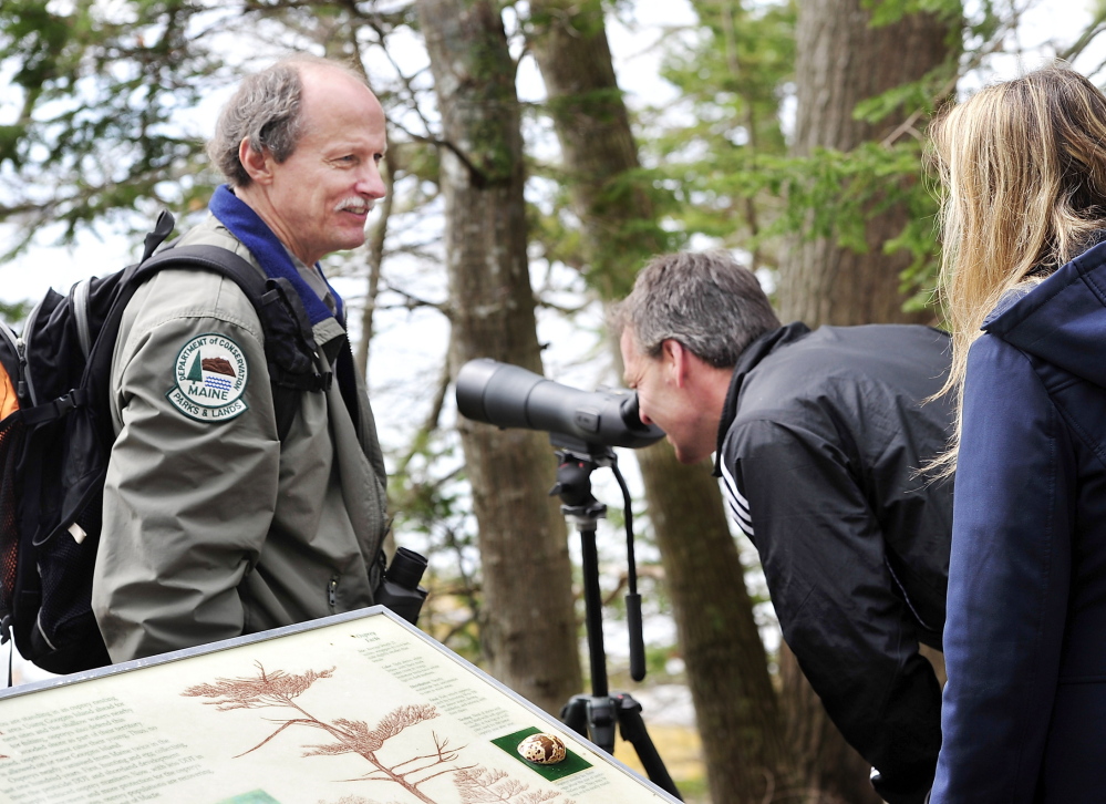 Park manager Andy Hutchinson lets Tom and Kristen Sandock – two visitors from Boxborough, Mass. – look through his 60x power scope at the Googins Island osprey nest in Wolfe’s Neck Woods State Park in Freeport. As they watch, he tells them about the osprey nesting program.