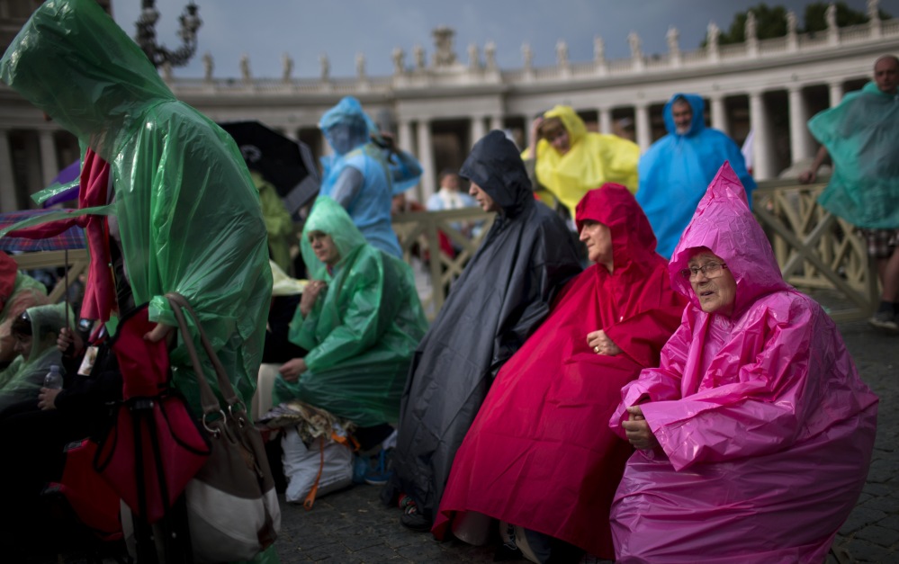 The faithful sit in St. Peter’s Square at the Vatican on Saturday. Benedict will attend the ceremony Sunday as Pope Francis elevates John XXIII and John Paul II to sainthood.