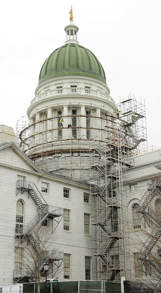 Workers build scaffolding around the State House dome on Wednesday in Augusta. A $1.3 million project entails restoring the dome’s copper sheathing and gilding the statue that tops it.