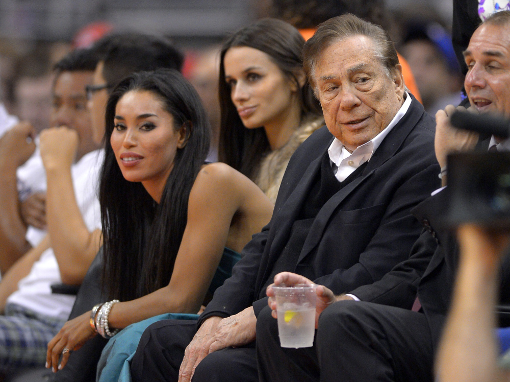 In this photo taken on Friday, Oct. 25, 2013, Los Angeles Clippers owner Donald Sterling, right, and V. Stiviano, left, watch the Clippers play the Sacramento Kings during the first half of an NBA basketball game in Los Angeles.
