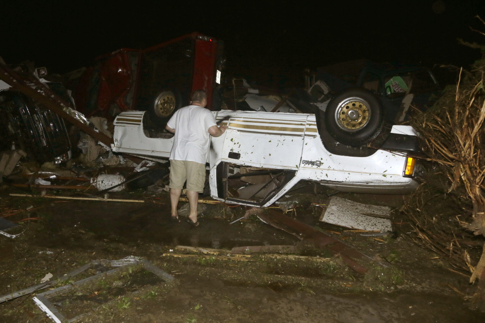 John Ward, an auto and RV dealer, looks at tornado damage to one of his trucks in Mayflower, Ark., Sunday.
