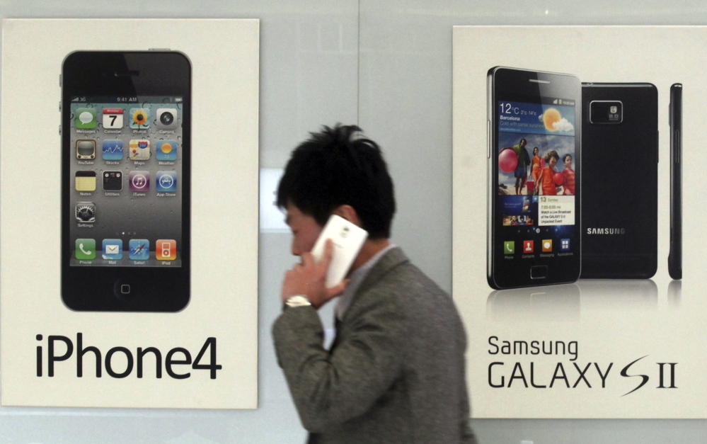 A man walks past banners advertising smartphones by Samsung and Apple at a mobile phone shop in Seoul, South Korea, in this 2013 file photo.