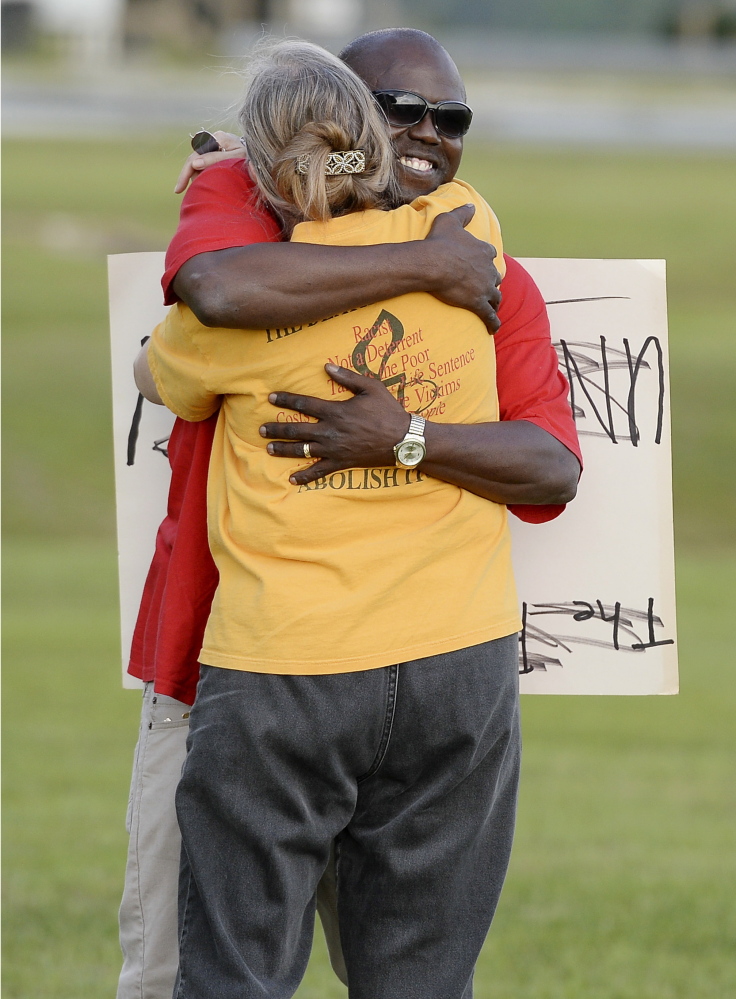 Herman Lindsey, who was exonerated from death row, back, greets a protester of the death penalty across the highway from the Florida State Prison last week.