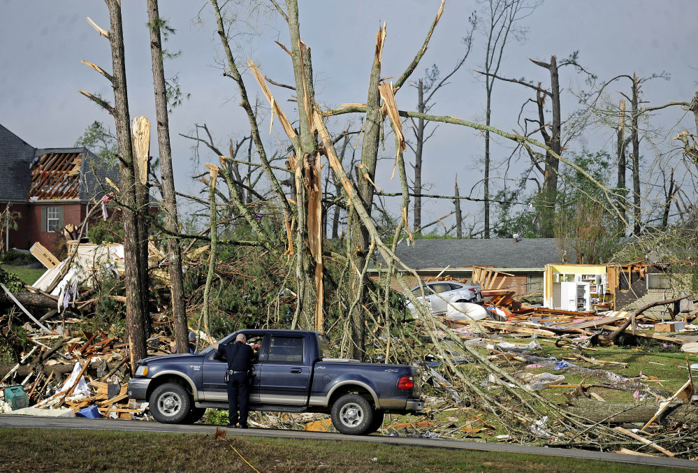 A police officer directs traffic in front of damaged homes Tuesday in Tupelo, Miss.