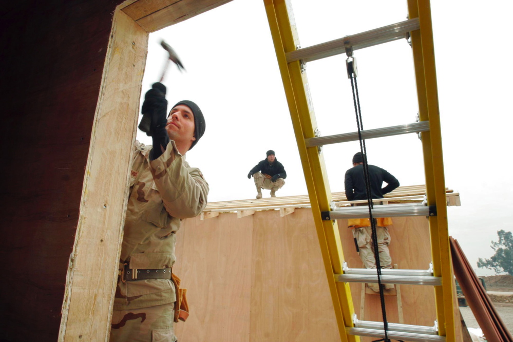 Sgt. Todd Kiilsgaard of Westbrook hammers a trim board on the front of a building that will be used by the Iraqi National Guard at a traffic control point near Mosul, Iraq, in 2004.