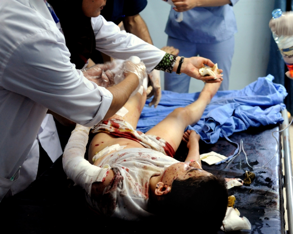 In this photo which AP obtained from the Syrian official news agency SANA, and has been authenticated based on its contents and other AP reporting, doctors treat a wounded Syrian boy at a hospital in Damascus, Syria, Tuesday. A series of mortar shells slammed into central Damascus on Tuesday, killing more than a dozen people and wounding scores, state media reported. The attacks in the Syrian capital came a day after President Bashar Assad announced his candidacy for the June 3 presidential election.