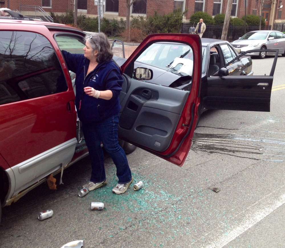Liz Bryant, guidance secretary for Portland High School, pours simulated blood on the cars as she helps set up a staged accident scene in front of the school on Cumberland Avenue in Portland.