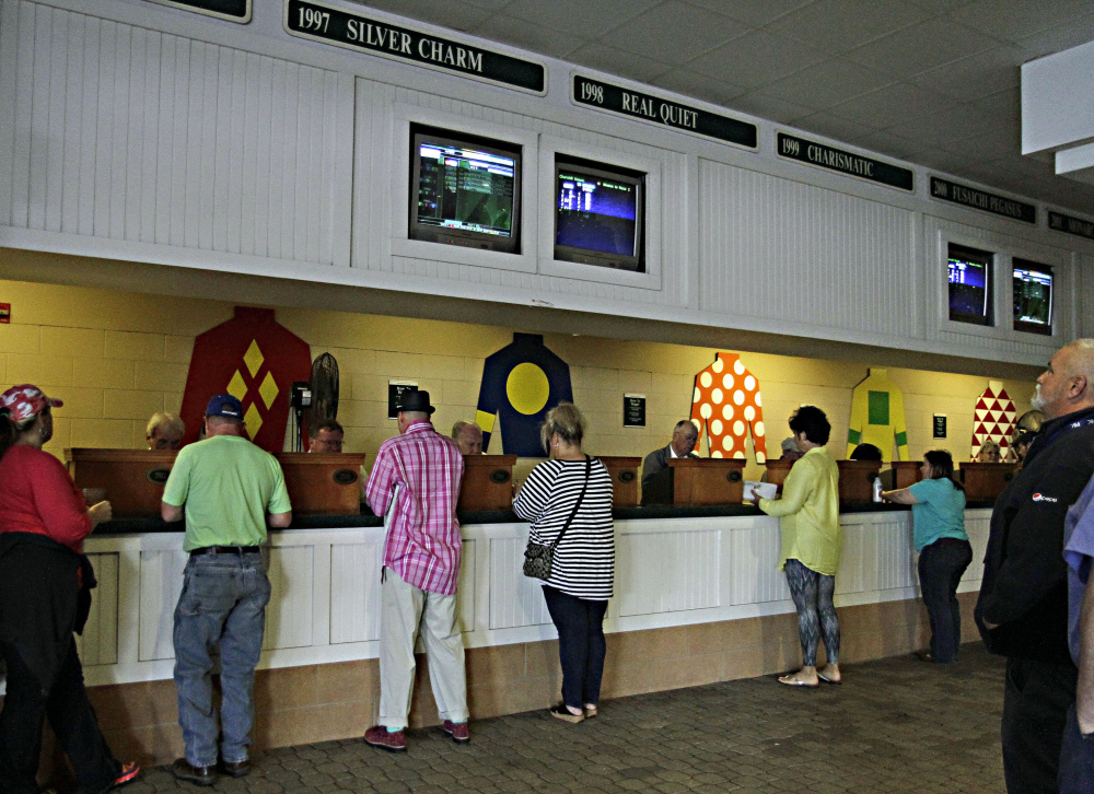 Horse racing patrons place wagers on races at Churchill Downs in Louisville, Ky., on Wednesday. Churchill Downs is taking a bigger cut of the money bettors place on its races.