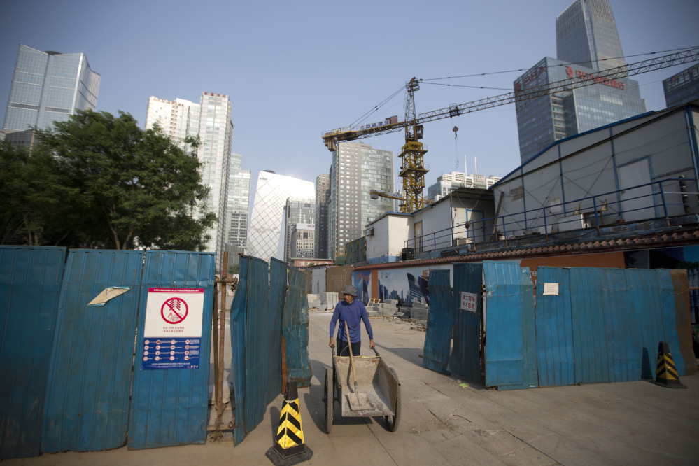 A worker pushes a cart as he walks out from a construction site at the Central Business District in Beijing Tuesday. The International Monetary Fund raised its economic growth forecast for China on Monday but warned that its financial system faces risks due to the rapid expansion of debt.