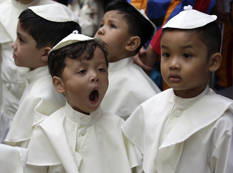 A boy dressed as a pope yawns as he prepares to join a parade in celebration of the canonization or the elevation to sainthood of Roman Catholic Pope John Paul II and Pope John XXIII Sunday at suburban Quezon city, northeast of Manila, Philippines.