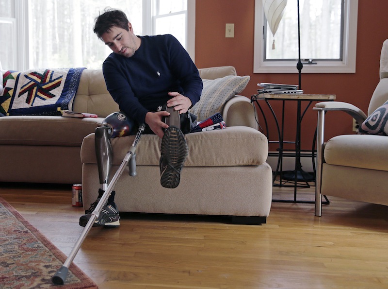 In this Friday, March 14, 2014 photo, Jeff Bauman adjusts one of his prosthetic legs at his home in Carlisle, Mass. Bauman, who lost both of his legs in the Boston Marathon bombings, helped identify one of the two brothers accused of setting off the explosions.