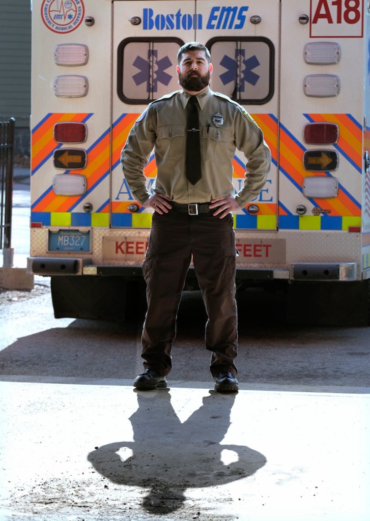 In this Thursday, March 20, 2014 photo, Boston Emergency Medical Services EMT Paul Mitchell stands next to an ambulance at his station in the Hyde Park neighborhood of Boston.