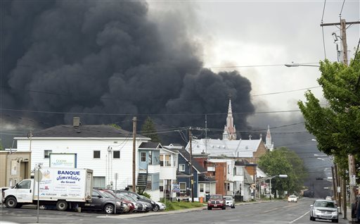 Smoke rises over Lac-Megantic from a deadly MM&A train derailment and explosion that killed 47 people in July 2013. A Canadian agency found that the railway had failed to report 20 previous derailments and two runaway train incidents in Canada.