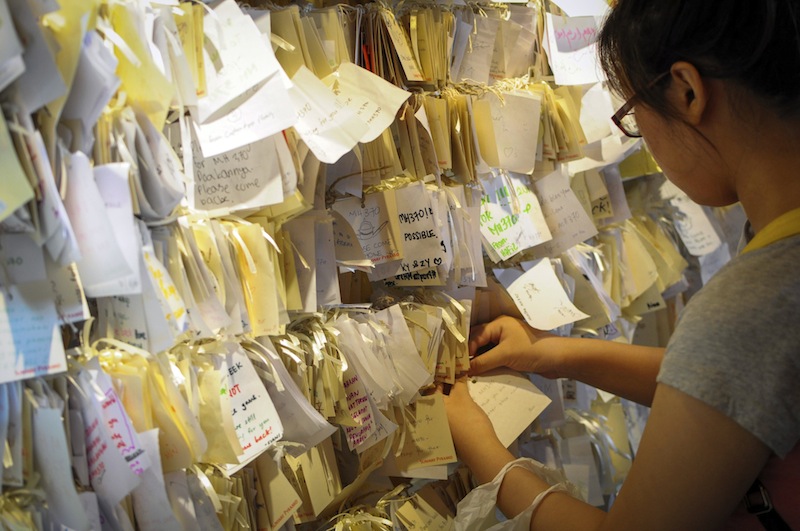 A woman ties a message card for passengers onboard the missing Malaysia Airlines Flight 370 at a shopping mall in Petaling Jaya, near Kuala Lumpur, Malaysia, Thursday, April 10, 2014.