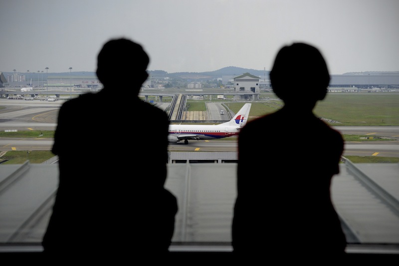 A couple is silhouetted as they watch a Malaysia Airlines plane on the tarmac from the viewing gallery at Kuala Lumpur International Airport in Sepang, Malaysia, Thursday, April 10, 2014. With hopes high that search crews are zeroing in on the missing Malaysian jetliner's crash site, ships and planes hunting for the aircraft intensified their search efforts on Thursday after equipment picked up sounds consistent with a plane's black box in the deep waters of the Indian Ocean.