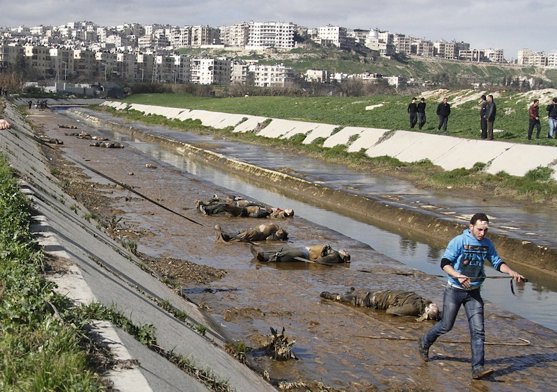 In this Jan. 29, 2013, file photo, a man walks past dead bodies in front of a river in the neighborhood of Bustan al-Qasr in Aleppo, Syria. The Britain-based Syrian Observatory for Human Rights said Tuesday that it has documented 150,344 deaths in the conflict that started in March 2011. The figure includes civilians, rebels, and members of the Syrian military. It also includes militiamen, fighting alongside President Bashar Assad’s forces and foreign fighters battling for Assad’s ouster on the rebels’ side. (AP Photo/Abdullah al-Yassin, File)