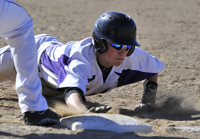 In this May 7, 2013, photo, Deering's Nick Bevilaqua dives back to first in a pickoff attempt as Biddeford hosts Deering in high school baseball action. In an effort to cut down on pitchers deceiving runners on pickoff moves, a new rule this year requires a pitcher to keep his feet together when starting a delivery, rather than having one foot in front or to the side.