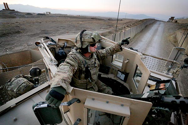 Sgt. Eric Crabtree of Hope, a gunner with the Convoy Escort Team of the 133rd Engineer Battalion of the Maine Army National Guard, rides in the gun turret on the way back from test firing his .50-caliber machine gun on the perimeter of Forward Operating Base Shank before departing on a convoy to Bagram Air Field in December.
