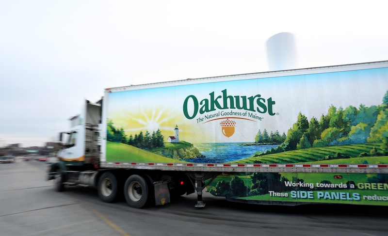 In this January 2014 file photo, an Oakhurst Dairy truck leaves the company headquarters on Forest Avenue in Portland. Two former and one current Oakhurst delivery drivers have filed a class-action lawsui claiming that the Portland-based company has failed for years to pay them overtime compensation in violation of state and federal wage laws.