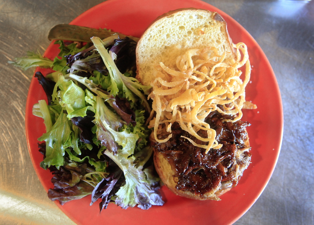 The Shipyard Brew Pub’s pulled pork sandwich is served with onion strings, a side salad with house vinaigrette dressing and a pickle.
