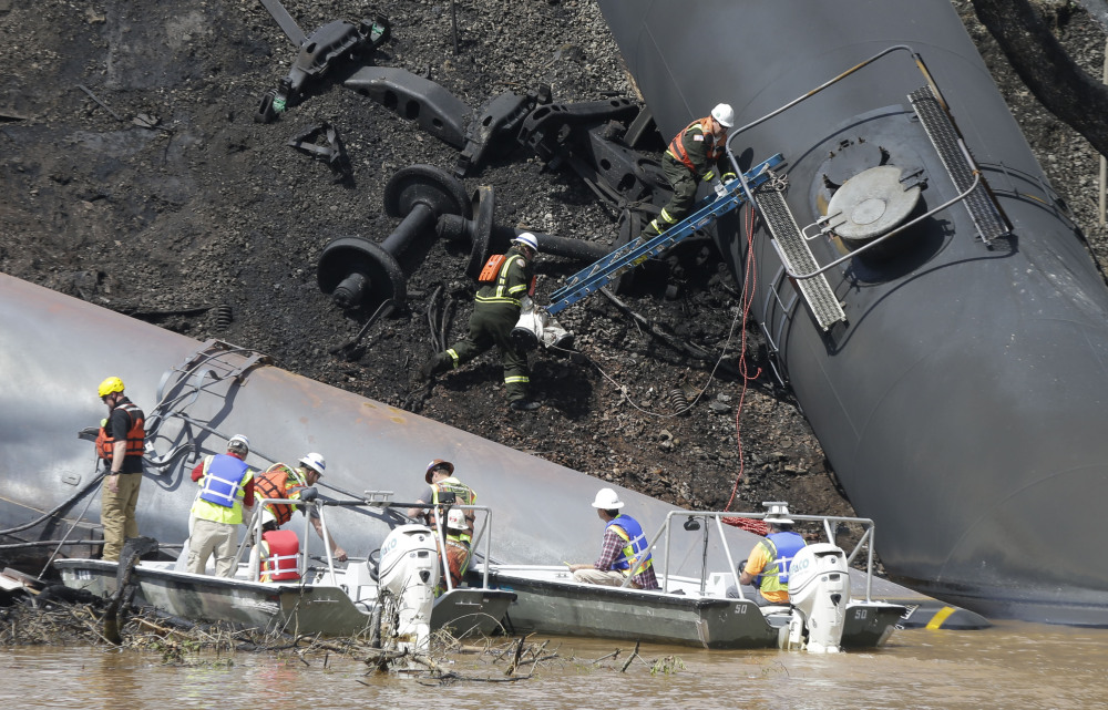 Workers remove damaged cars Thursday along the tracks where several CSX tanker cars carrying crude oil derailed and caught fire along the James River near downtown Lynchburg, Va. Two cranes were lifting derailed cars and moving them to a new track.