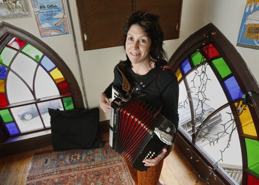 Blainor McGough, 39, a puppeteer and musician who manages the Mayo Street Arts performance venue in Portland, plays the accordion at her home Thursday. A native Mainer who lived and worked in, among other places, Florida and Mexico, she eventually returned. “I realized there was no place else I’d want to live,” she said.