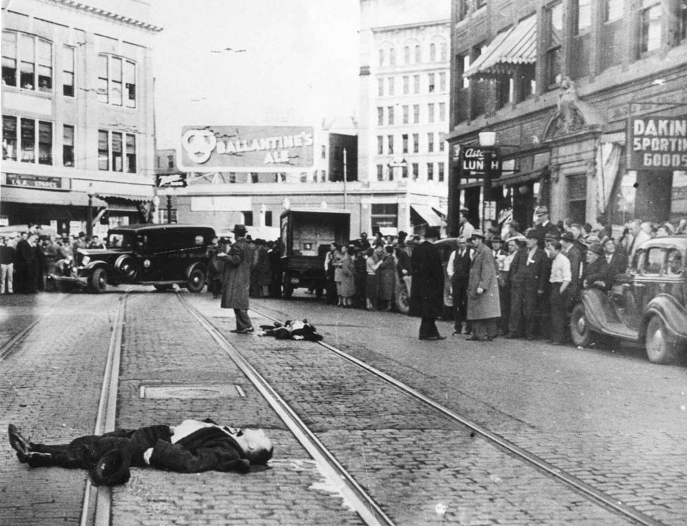 Gangsters Al Brady, foreground, and Clarence Lee Shaffer Jr., background center, lie on Central Street were they were killed by government agents Oct. 12, 1937, in Bangor. FBI agent Walter R. Walsh, who posed as a salesman, was wounded in the incident.