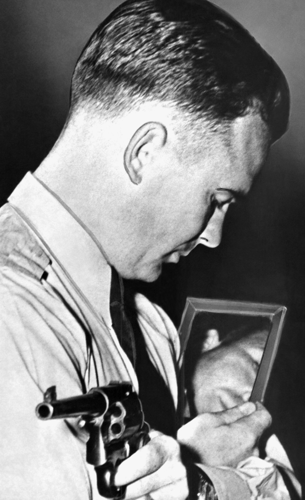 Federal Agent Walter R. Walsh demonstrates how to aim a gun using a mirror, in Quantico, Va., in 1937. He also trained Marine snipers and competed in the 1948 Olympics.