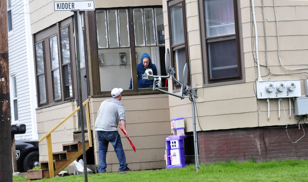 A man uses a toy shovel to scoop up large pieces of glass from a broken window on Clinton Avenue in Winslow on Thursday. A man was injured after he broke windows and damaged doors with a snow shovel at the apartment building.