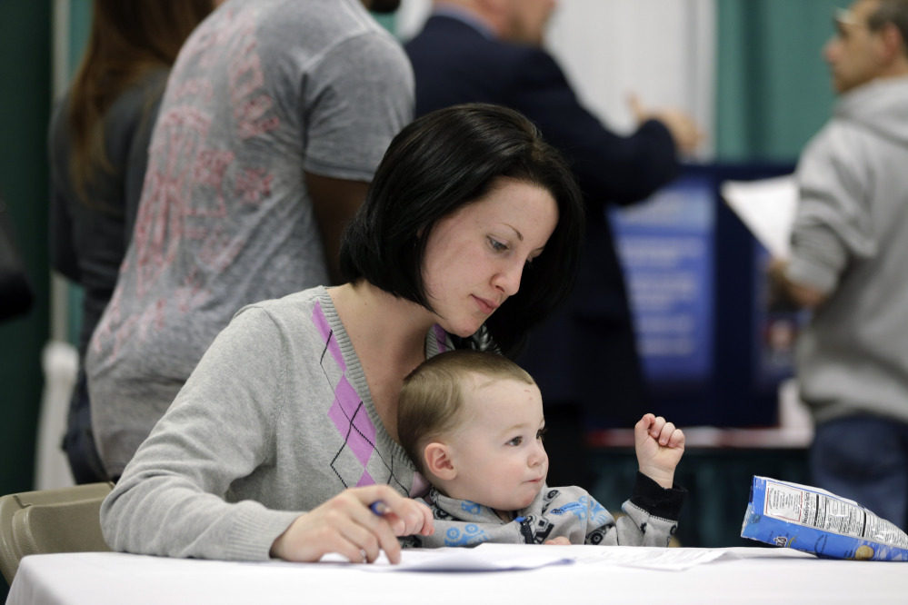 Sarah Keegan of Windham, N.Y., with her son Kevin, fills out paperwork during a job fair recently at Columbia-Greene Community College in Hudson, N.Y.