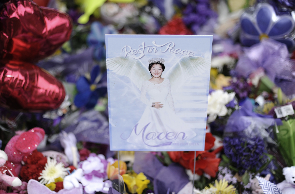 A sign with a photograph of Maren Sanchez stands among a flowers left at a memorial rock for Sanchez at Jonathan Law High School in Milford, Conn., on Friday. Sanchez was fatally stabbed inside the school last Friday hours before her junior prom.