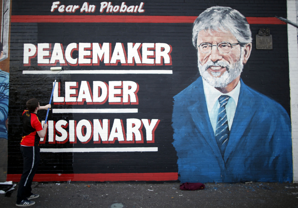 A man adds the finishing touch to a newly painted mural of Gerry Adams in West Belfast, Northern Ireland, on Friday, as police continued to question the Sinn Fein leader.