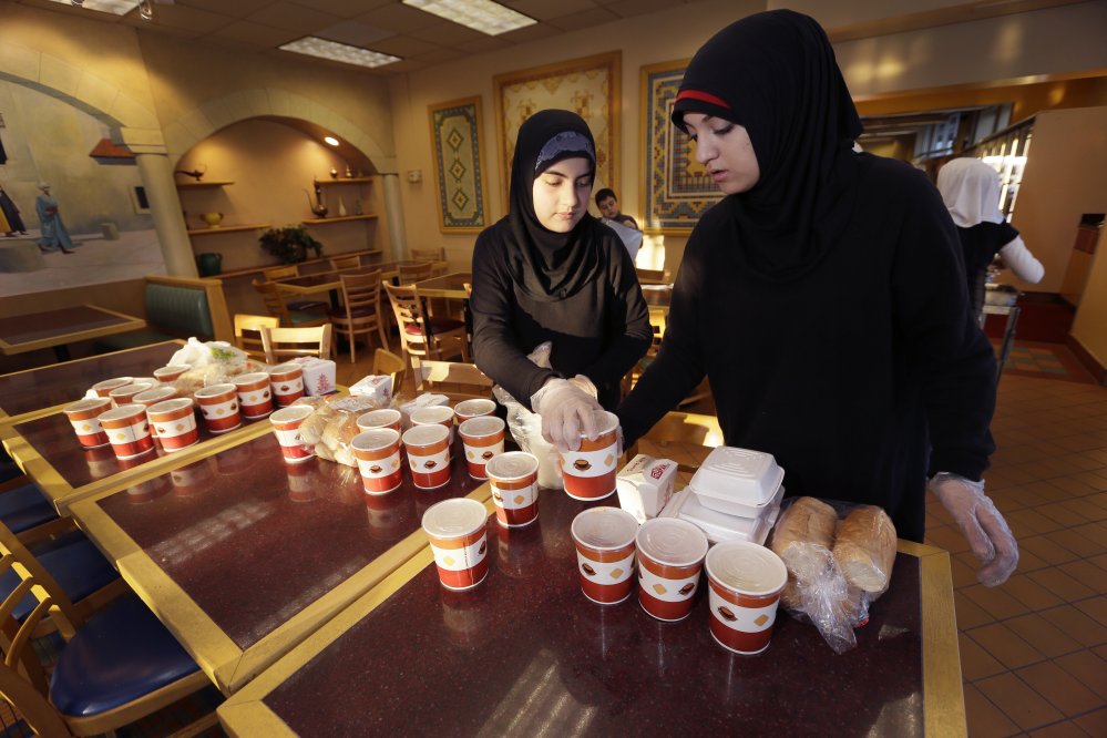 Volunteers Wafaa Dabaja, left, and Zahraa Dabaja prepare meals from food provided by the Yasmeen Bakery in Dearborn, Mich.