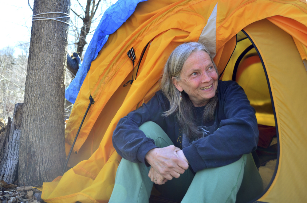 Nina Miller sits in the opening of her tent in the woods behind her home, where she has slept for more than 170 nights.
