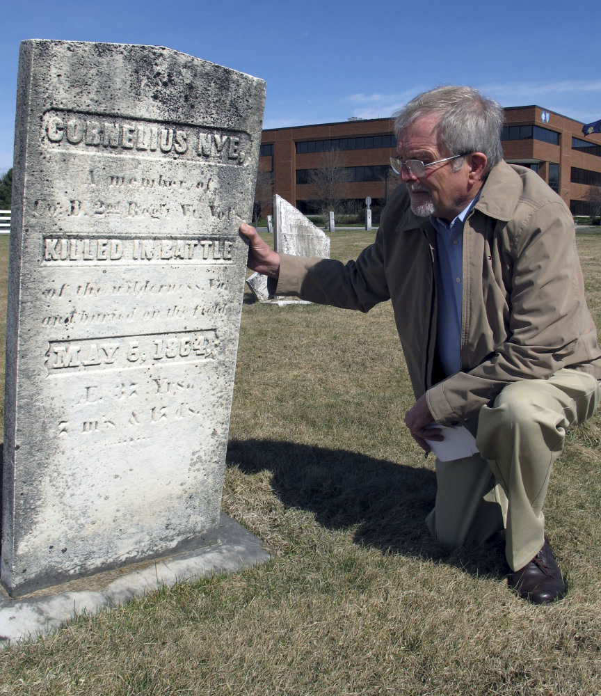 Civil War historian Howard Coffin kneels in Berlin, Vt., at the marker of a Vermont soldier killed at the Battle of the Wilderness in Virginia on May 5, 1864.