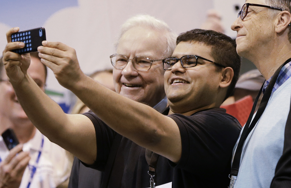 An unidentified shareholder takes a selfie with Warren Buffett, left, and Bill Gates, right, Saturday in Omaha, Neb.