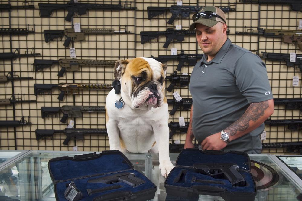 Engage Armaments owner Andy Raymond is shown Thursday at his store in Rockville, Md., with his dog Brutus. He backed away from plans to sell smart guns after getting threats.