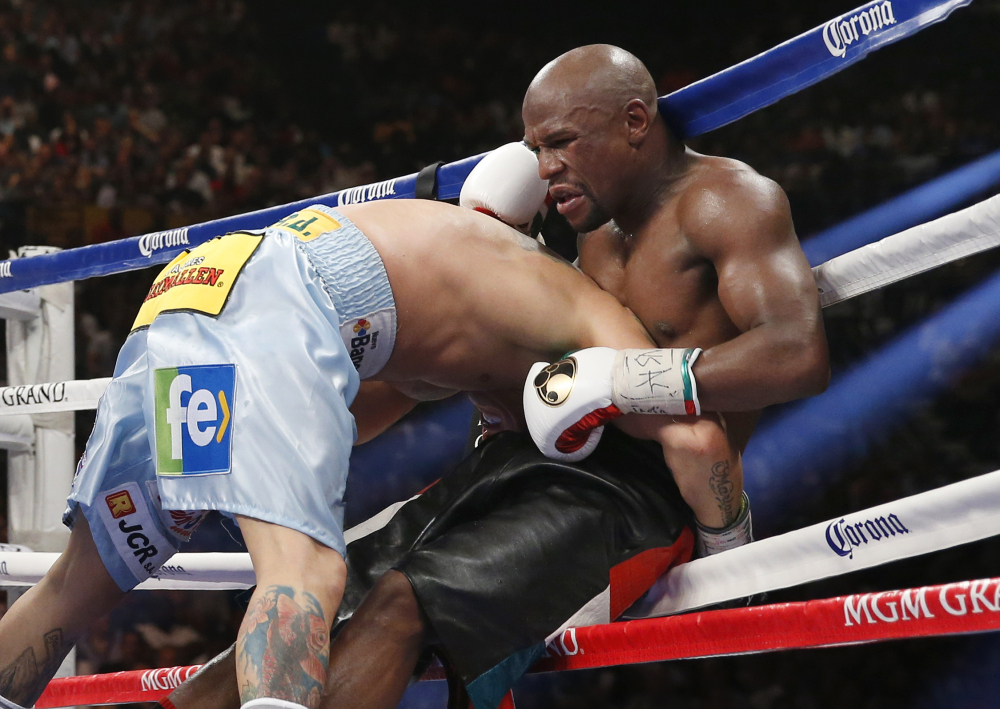 Floyd Mayweather Jr. is driven through the ropes by Marcos Maidana in their WBC-WBA welterweight title boxing fight on Saturday, in Las Vegas. Mayweather won by majority decision.