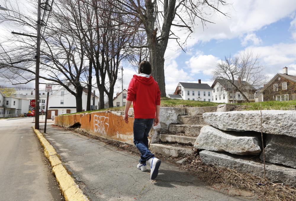 A boy passes vacant lots at the corner of Green and South streets in Biddeford. The city demolished the home of convicted murderer Rory Holland and another house to make way for a park expansion.