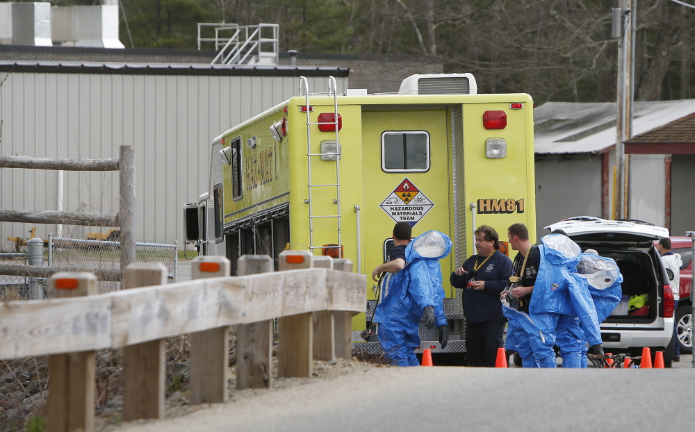 Hazardous materials team members from the Portsmouth Naval Shipyard remove hazmat suits after responding to an explosion at the sewage treatment plant in Kennebunk on Monday.
