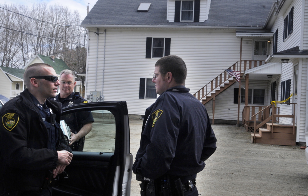 Gardiner police confer Monday while guarding an apartment building on Cannard Street where a father and son lived together. Maine State Police searched their apartment.