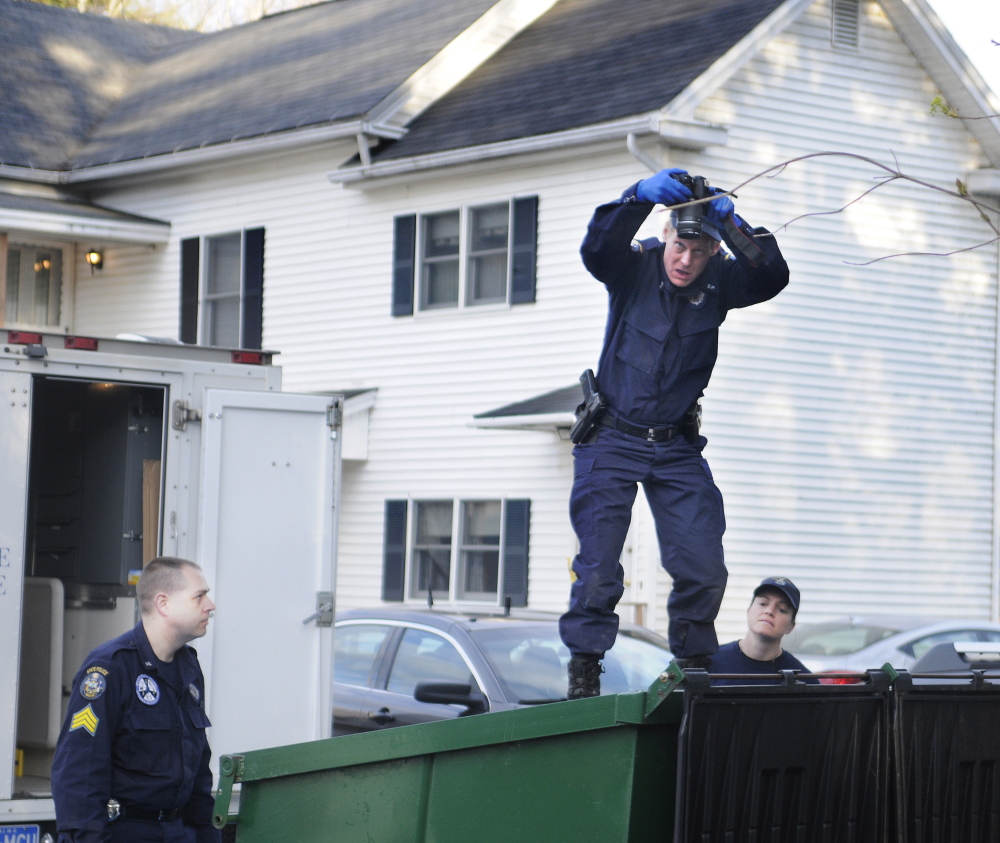 Maine State Police Detective Terry James, center, photographs the interior of a Dumpster on Monday outside of the apartment that Leroy Smith Jr. shared with his son, Leroy Smith III, in South Gardiner. Detective Sgt. Jason Richards, left, and Trooper Breanne Petrini searched the Dumpster after the elder Smith’s body was recovered in Richmond.