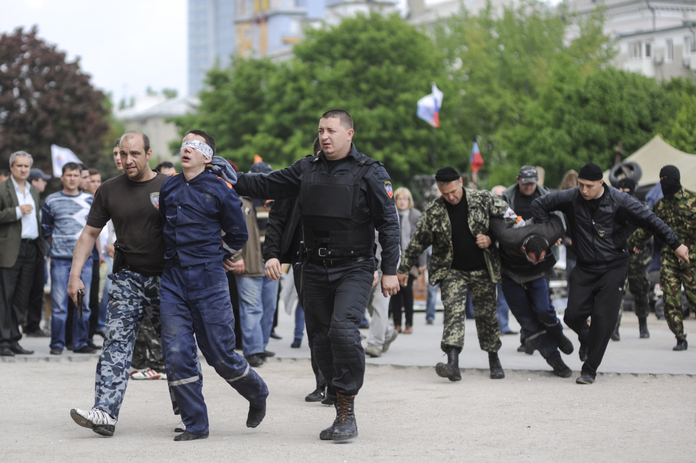 Pro-Russian activists convey captured fire service employees to the regional administration building in the city of Donetsk, in eastern Ukraine, on Monday. Pro-Russian forces and their supporters have been seizing and ransacking government buildings across eastern Ukraine amid a mounting anti-government insurgency that is threatening to tip the former Soviet nation into widespread civil conflict.