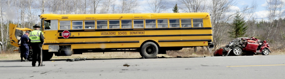 A small vehicle is pulled away from a Vassalboro School District bus after it slammed into the bus, which was parked on Route 3 in South China on Monday.
